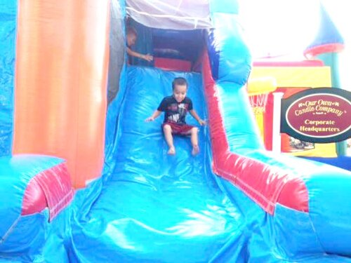 Young boy enjoying the slide in a bounce house.