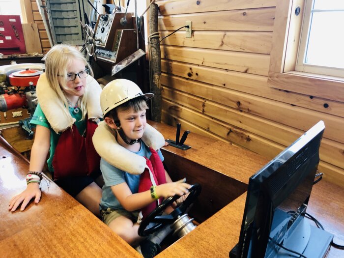 Two kids playing with the catboat simulator at the Lawson Boating Center