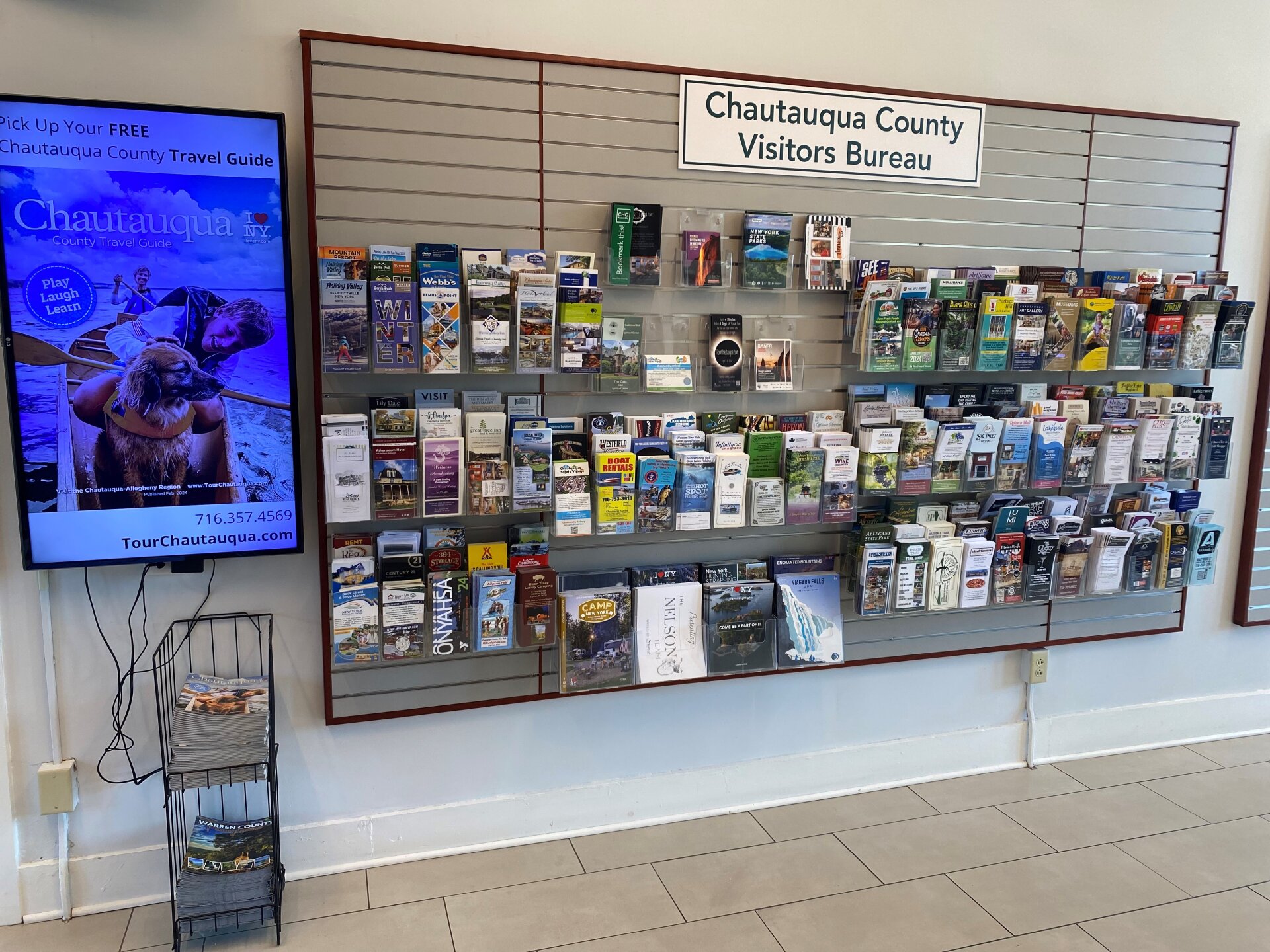 Chautauqua County Visitors Bureau travel guides in rack and on tv screen