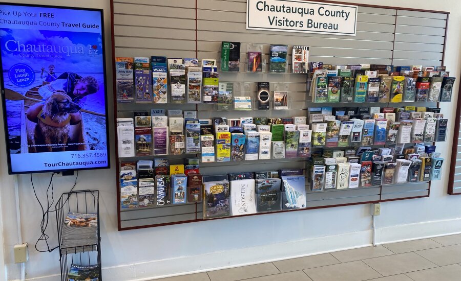 Chautauqua County Visitors Bureau travel guides in rack and on tv screen