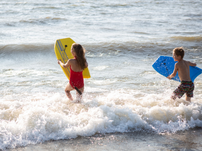 A boy and girl with body boards playing on a Lake Erie beach.