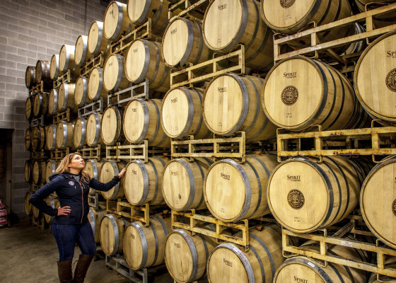 A women standing next to barrels of spirits at Southern Tier Distilling Co.