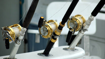 Photo of three fishing rod being held on a boat.