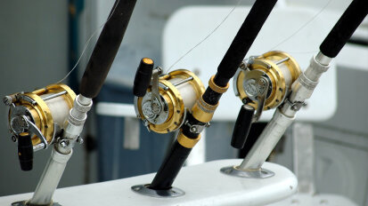 Photo of three fishing rod being held on a boat.