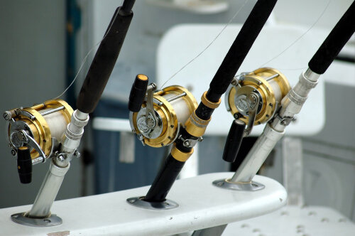 Photo of three fishing rod being held on a boat.