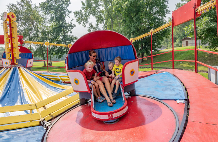 3 kids and an adult riding the Tilt-a-Whirl at Midway State Park, laughing