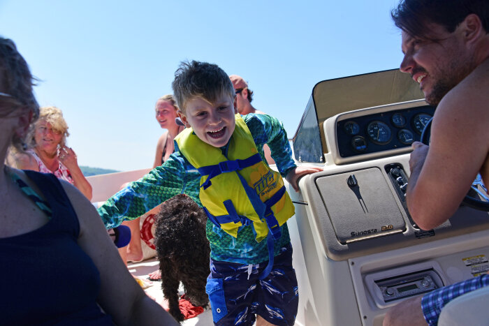 Boy in a life vest laughing on a boat