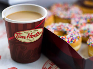 A Tim Hortons cup of coffee and box of doughnuts.