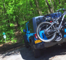 Blue mountain bike hung on the back of a Jeep at Long Point Heather Canal.