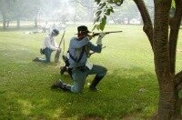 Two men firing muskets reenacting the civil war.