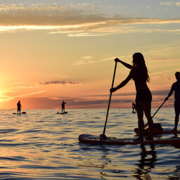 People standup paddleboarding at sunset on Lake Erie's Sunset Bay, NY