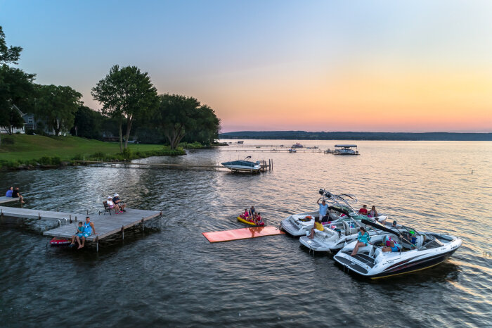 Three boats tied up together on Chautauqua Lake at sunset with kids playing in the water